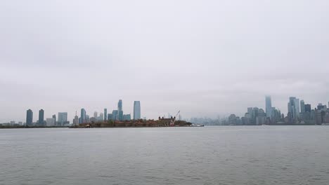 Zeitrafferaufnahme-Des-Hudson-River-Und-Ellis-Island-Mit-Der-Skyline-Von-Manhattan-Im-Hintergrund