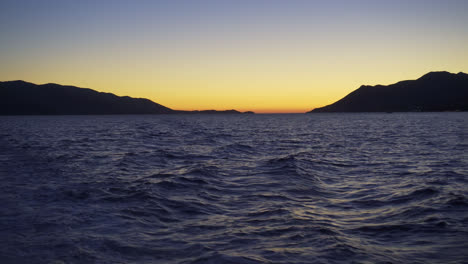Meereswellen-Mit-Silhouettierten-Bergen-Im-Hintergrund-Während-Des-Sonnenuntergangs