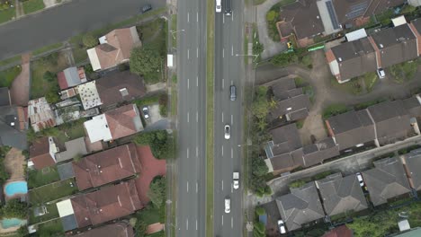 4K-aerial-dual-carriageway-or-divided-highway-among-the-neighborhood-homes,-houses-and-properties-with-traffic-drone-forward-top-down-fly-over
