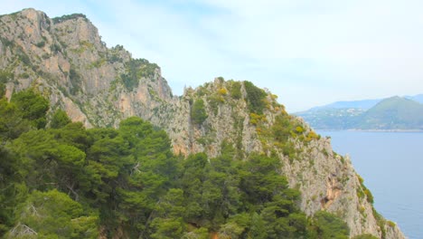 Pan-Aufnahme-Von-Steilen,-Mit-Grüner-Vegetation-Bedeckten-Klippen-Auf-Der-Insel-Capri,-Italien,-An-Einem-Bewölkten-Tag
