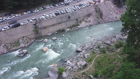 Aerial-shot-of-water-stream-near-the-street-of-Manali