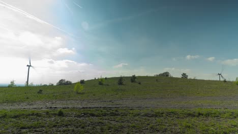 Electric-wind-turbine-farm-on-top-of-old-mining-heap-overgrown-with-grass,-time-lapse-view
