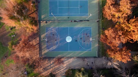 Statische-Draufsicht-Auf-Eine-Gruppe-Von-Leuten,-Die-Basketball-Auf-Den-Plätzen-Des-Parque-Araucano-Spielen,-Umgeben-Von-Herbstbäumen