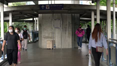 People-walking-overhead-bridge-walkway-towards-SalaDaeng-Skytrain-station-in-Bangkok