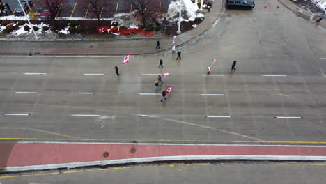 Group-Of-Truckers-With-Canadian-Flags-Marching-On-The-Street-During-Freedom-Convoy-Protest-In-Windsor,-Ontario,-Canada