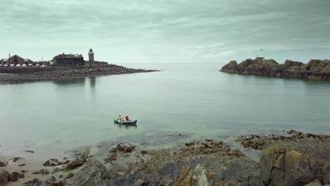 Ein-Einsames-Kanu,-Das-Auf-Dem-Meer-In-Portpatrick,-Schottland,-Mit-Stimmungsvollem-Himmel-Und-Ruhiger-See-Segelt