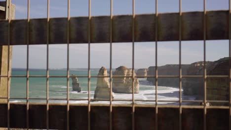 Waves-lapping-against-Twelve-Apostles-through-a-caged-fence---point-of-view