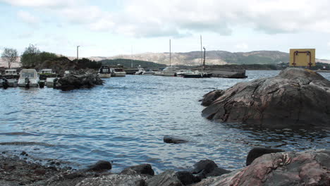 Blick-Auf-Einen-Kleinen-Hafen-Mit-Winzigen-Booten,-Die-Sich-Im-Wasser-Eines-Fjords-Bewegen,-Aufgenommen-In-Einer-Zeitrafferaufnahme-Aus-Norwegen