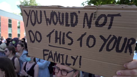 A-protestor-holds-up-a-cardboard-placard-that-reads,-"You-would-not-do-this-to-your-family