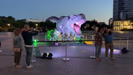 People-taking-pictures-with-the-dinosaur-decoration-in-front-of-the-cinema-after-watching-the-movie-Jurassic-World-Dominion