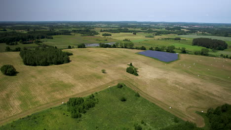 Aerial-view-of-a-large-agricultural-field-after-harvesting-on-a-sunny-day-with-a-small-solar-panel-farm