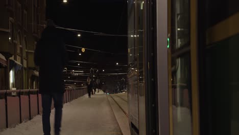 Winter-city-night:-Train-door-opens,-man-steps-out-onto-snowy-street
