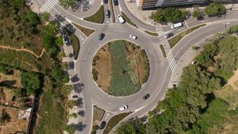 Suburban-roundabout-with-driving-vehicles-in-Spain,-aerial-top-down-view