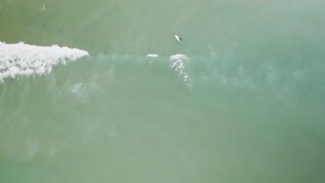 Surfing-wading-out-through-waves-to-catch-surf-overhead-aerial
