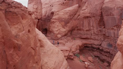 Approaching-aerial-view-of-a-couple-exploring-red-rock-formations-in-Utah