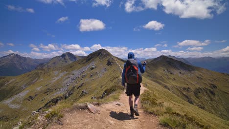 Static-centered,-hiker-walks-alpine-ridge,-vast-mountain-landscape,-Fiordland,-Kepler-Track-New-Zealand