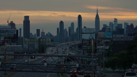 Queens,-New-York,-Highway-Mit-Der-Skyline-Von-Manhattan-Bei-Sonnenuntergang-In-Der-Ferne