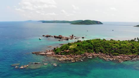 Aerial-Raise-Up-View-of-Exotic-Rocky-Coast-island,-Phu-Quoc-Vietnam,-Paradise-Coastline-Landscape-of-Wild-Green-Lands-Surrounded-by-Clear-Turquoise-Sea