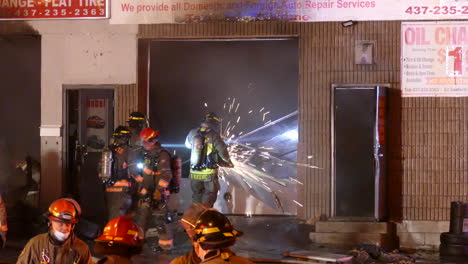 Equipo-De-Bomberos-Con-Corte-De-Sierra-Circular-A-Través-De-Puertas-De-Garaje-De-&#39;danforth-And-Warden&#39;-Taller-De-Reparación-De-Carrocerías-De-Automóviles-En-Scarborough,-Toronto