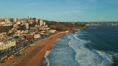 Aerial-view-flying-down-Reñaca-golden-sand-waterfront-with-sunny-scenic-tourism-retreat-beach-cityscape