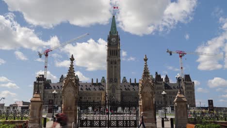 Parliament-of-Canada,-Centre-Block,-on-a-partially-cloudy-day-in-summer-before-Canada-Day-with-construction-cranes-in-Ottawa,-Canada---4K