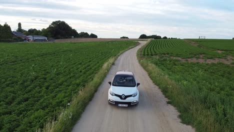 White-car-driving-in-the-middle-of-the-dirt-road