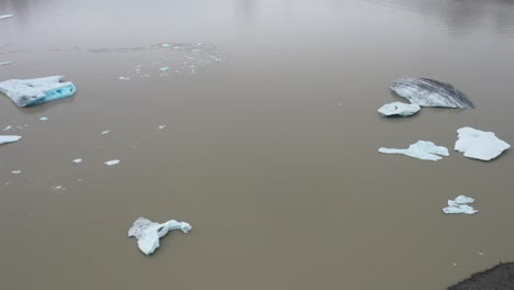 Chunks-of-glacier-blue-ice-in-Iceland-floating-in-water-with-drone-video-moving-sideways