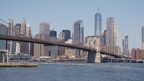 Manhattans-Finanzviertel-Mit-Dem-One-World-Trade-Center-Und-Der-Brooklyn-Bridge-An-Einem-Sonnigen-Tag,-Statische-Aufnahme-Vom-Ufer-Des-East-River