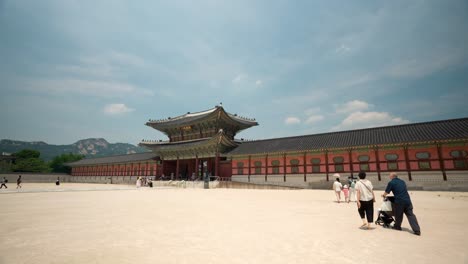 Atrás-De-Una-Familia-Joven-Con-Un-Niño-Y-Una-Pareja-Mayor-Caminando-Hacia-La-Puerta-Heungnyemun-En-El-Palacio-Gyeongbokgung,-Seúl,-Corea-Del-Sur