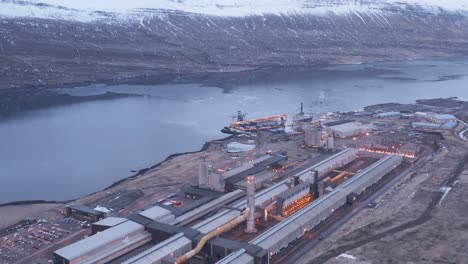 Massive-industrial-facility-on-fjord-shore-in-east-Iceland,-aerial