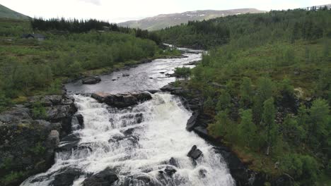 Aerial-View-Of-River-Cascading-Down-Rocks-Surrounded-By-Green-Wilderness-Landscape-In-Hardangervidda-National-Park