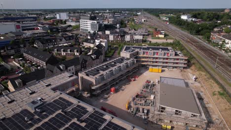 Movimiento-Aéreo-Hacia-Atrás-Que-Revela-El-Sitio-De-Construcción-Ubuntuplein-En-Desarrollo-Urbano-Proyecto-De-Inversión-Inmobiliaria-En-El-Nuevo-Barrio-De-Noorderhaven-Con-Paneles-Solares-En-La-Azotea