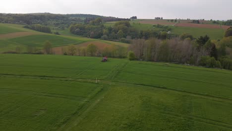 downward-looking-drone-footage-of-large-green-meadows-where-a-tractor-is-driving