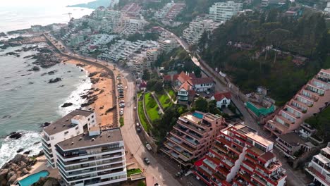 Aerial-truck-left-of-luxury-apartments-and-houses-in-hillside-near-the-sea-shore-in-sector-5-of-Reñaca,-Viña-del-Mar,-Chile