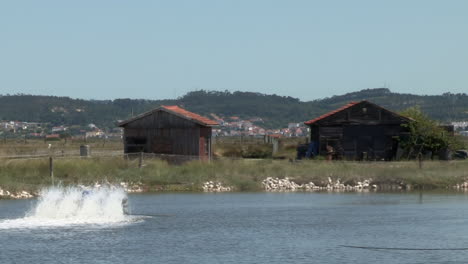 Fischteich-Mit-Zwei-Holzhäusern-Im-Hintergrund