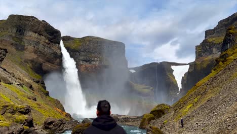 Man-enjoying-stunning-landscape-with-waterfall-in-sunny-day,-Iceland