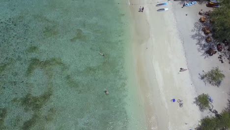 Küstenstreifen-Voller-Sonnenschirme-Und-Sonnenliegen,-Ruhige-Luftaufnahme,-Flug,-Nach-Oben-Geneigte-Drohnenaufnahmen-Von-Gili-T-Beach,-Bali,-Indonesien-Im-Sonnigen-Sommer,-Filmische-Ansicht-Von-Oben,-Reiseführer-Von-Philipp-Marnitz