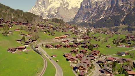 aerial-drone-footage-pushing-out-with-views-of-mountain-train-leaving-grindelwald-in-swiss-alps-at-100%-view