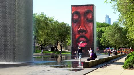 Gente-Disfrutando-Del-Parque-Del-Centro-De-La-Ciudad-Con-Obras-De-Arte-De-La-Fuente-De-La-Cara-Masculina-Afroamericana