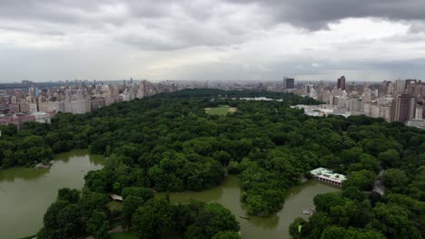 Aerial-view-overlooking-The-Central-Park-Lake,-in-cloudy-NYC,-USA---tilt,-drone-shot
