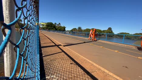 steady-shot-next-to-a-fence-of-the-bridge-that-crosses-the-lake-in-the-city-park-of-Brasilia-where-some-maintenance-people-pass