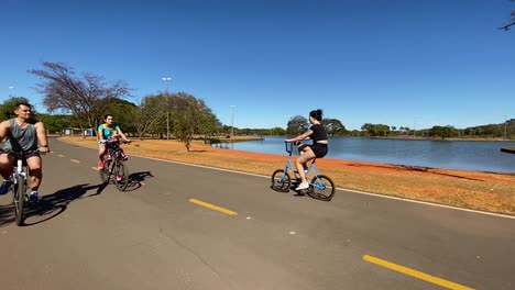 Zeitlupenaufnahmen-Von-Radfahrern,-Die-An-Einem-Der-Seen-Im-Stadtpark-Von-Brasilia-Entlang-Fahren