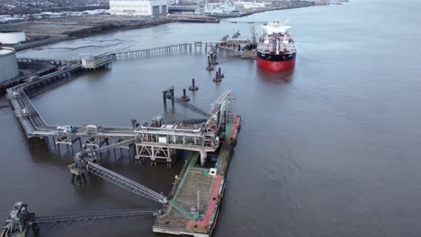 Aerial-view-International-oil-tanker-docked-at-refinery-loading-terminal-depot-orbit-over-pier-left