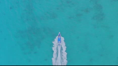 Aerial-top-down-tracking-of-motorboat-sailing-on-turquoise-caribbean-sea-water,-Dominican-Republic