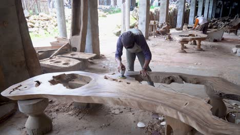 Making-wooden-furniture-at-carpenter-workshop,-worker-grinds-table-top