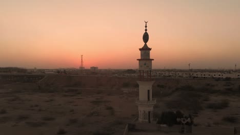 Luftaufnahme-Des-Minaretts-Einer-Moschee-In-Der-Nähe-Der-Autobahn-In-Karatschi-Vor-Dem-Orange-gelben-Sonnenuntergangshimmel