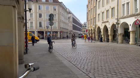 Static-wide-shot-of-pedestrian-and-cyclist-with-face-mask-along-the-way-in-city-center-of-german-city-during-covid-19-pandemic