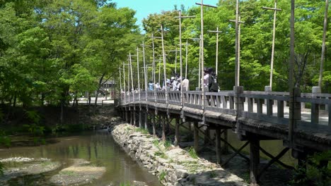 Gente-Disfrutando-De-La-Vista-Desde-El-Viejo-Puente-De-Madera-Con-árboles-Verdes-En-El-Fondo-En-El-Pueblo-Folclórico-Coreano-En-La-Ciudad-De-Yongin,-Seúl,-Corea-Del-Sur