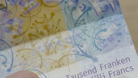 Macro-shot-of-male-person-holding-one-thousand-chf-swiss-franc-banknote