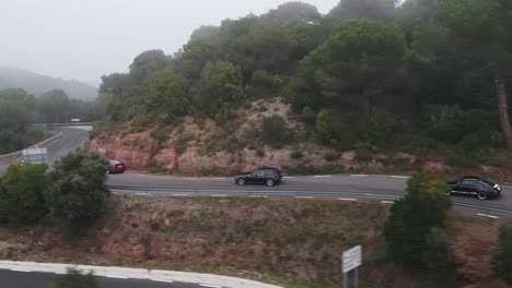 Aerial-view-following-three-high-end-valuable-cars-driving-fast-along-Barcelona-woodland-winding-roads-tracking-left